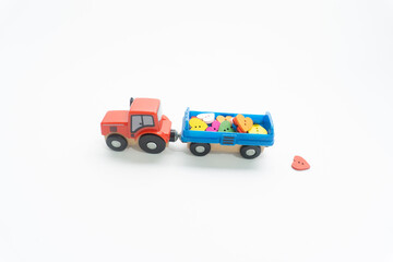 Creative concept of small red tractor toy, blue trailer toy and colorful hearts.