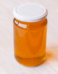 a jar full of honey alone with antique white wooden background