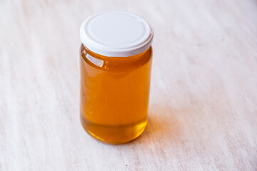 a jar full of honey alone with antique white wooden background