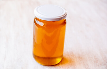 a jar full of honey alone with antique white wooden background