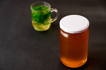 Jar of honey with a cup of tea