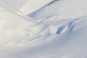 Beautiful winter background with snowy ground. Natural snow texture. Wind sculpted patterns on snow surface.