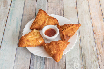 Vegetable samosas fried in oil with sauce in the center to dip