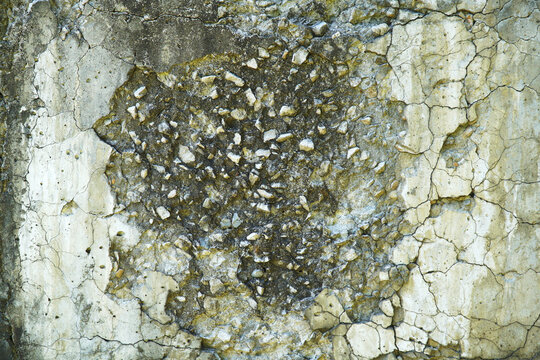 Concrete wall with cracked and crumbling plaster.