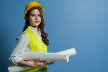 Women engineer with yellow safety helmet and holding blueprint