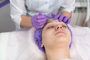 Female client is having facial treatment with the help of eye loop. Cosmetology and skin care routine.