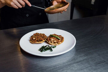 Latin woman chef cooking tostadas of Bacalao a la Vizcaina traditional mexican food in a restaurant kitchen in Mexico