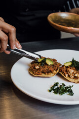 Latin woman chef cooking tostadas of Bacalao a la Vizcaina traditional mexican food in a restaurant kitchen in Mexico