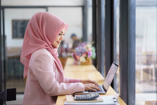 Beautiful muslim business woman working on laptop computer at co-working space.