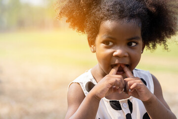 Fototapeta premium Cheerful African American toddler little girl playing outdoor in the park. Cute black people child girl with hair curly laughing outdoor