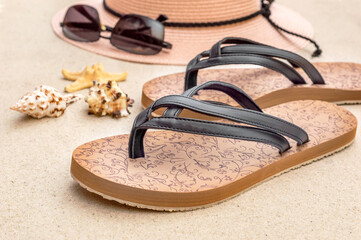 Flip flops with beach hat and seashells on sand. Vacation concept.