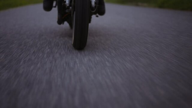 Motorcycle Wheel Running on Gray Concrete Road With a Glimpse of Lush Forest