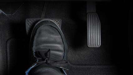 Man foot and accelerator and brake pedal inside the car or vehicle and copy space which black color...