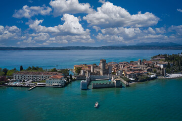 Fototapeta na wymiar Aerial view of the island of Sirmione. Sirmione, Lake Garda, Italy. Peninsula on a mountain lake in the background of the alps. Castle on the water in Italy. Panorama of Lake Garda.
