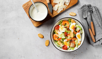 Fresh Shrimp Caesar Salad with parmesan cheese and Croutons. Gray background, top view, space for text.