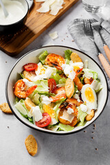Fresh Shrimp Caesar Salad with parmesan cheese and Croutons. Gray background.