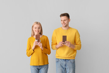 Young couple with tasty chocolate on grey background