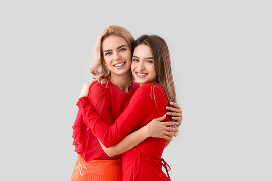 Beautiful young sisters on light background