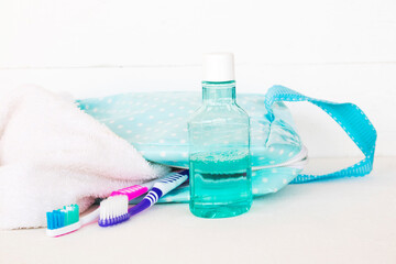 mouthwash, toothbrush health care for oral cavity with terry cloth, bag arrangement flat lay style on background white wooden