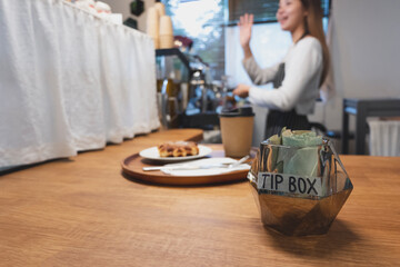 Naklejka na ściany i meble Tip box in a cafe with background of a joyful friendly barista