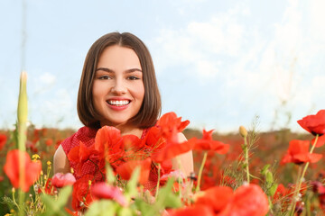 Naklejka premium Beautiful young woman in poppy field