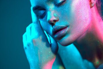 Fashion art. Model girl in colorful bright sparkles and neon lights posing in studio, portrait of...