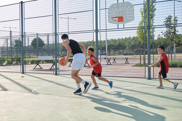 Three brothers playing basketball, one of them has a leg prosthesis. Siblings playing basket.
