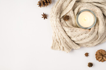Top view photo of lighted candle in candlestick sweater pine cones and anise on isolated white...