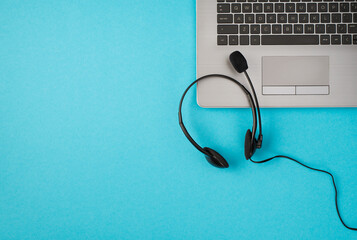 Top view photo of headphones with microphone on laptop on isolated pastel blue background with copyspace