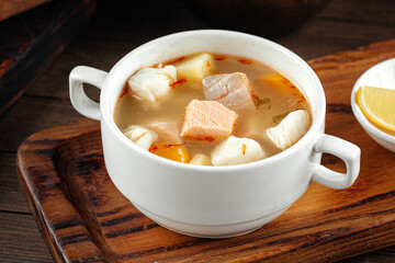 Bowl of ukha fish soup with lemon on the wooden background