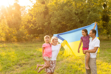 Flag Ukraine in hands of little girl in field. Child carries fluttering blue and yellow flag of Ukraine against background field.