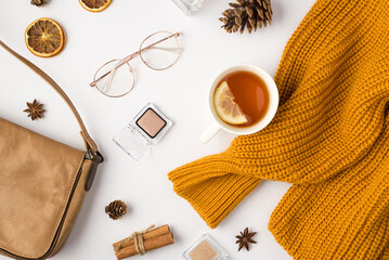 Top view photo of orange sweater cup of tea with lemon eyeshadows cosmetics stylish glasses pine...