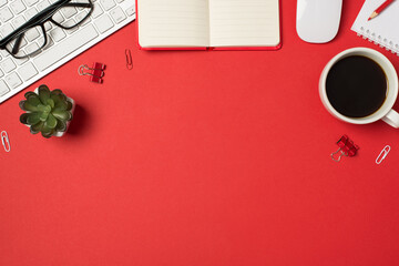 Top view photo of workplace keyboard glasses binder clips flowerpot mouse pencil diaries and cup of coffee on isolated red background with blank space