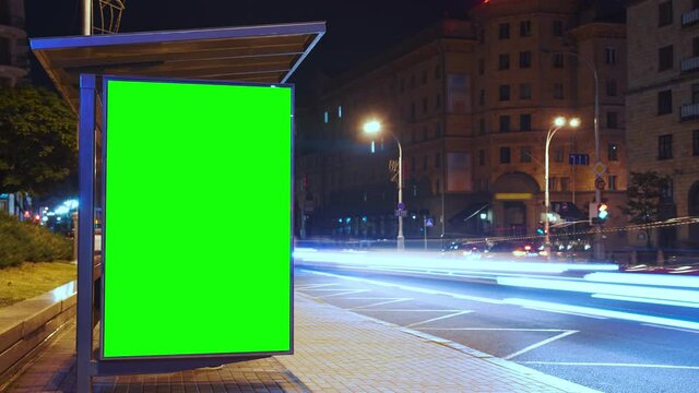 Billboard with a chroma key green screen on n bus stop at night. Time Lapse.	

