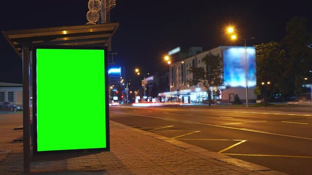 Billboard with a chroma key green screen on n bus stop at night. Time Lapse.	
