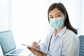 Asian female doctor using laptop computer for working in hospital. 