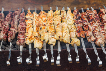 Three types of meat on skewers on the grill. Pieces of pork, chicken and lamb on skewers on the grill.