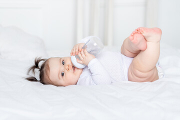 baby with a bottle on the bed at home, baby food concept