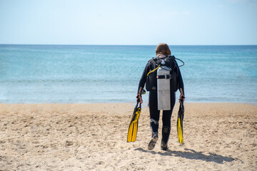 Scuba Diver. Diver girl walks along the beach towards the sea