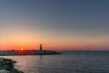 Fototapeta premium The small lighthouse at the entrance of the harbour in Tel Aviv at sunset