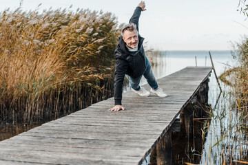 Healthy fit man working out on an old rustic wooden jetty