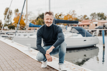 Fit athletic man crouching on the quay of a marina