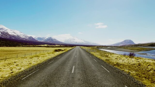 Endless Horizon of the Road Surrounded by Mountain Ranges Under a Blue Sky