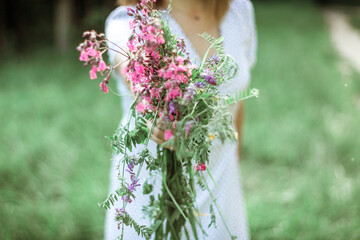 a married woman holds out a bouquet of wild flowers to the camera. The hand of a woman with an engagement ring holds lilac wildflowers. Selective Focus