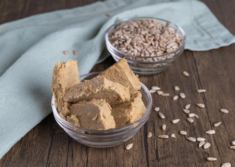 Halva, also Halvah or Halwa, Asian-Turkish homemade sweet dessert made from fried sunflower seeds and sugar syrup, served on a brown wooden background with a textile cloth.