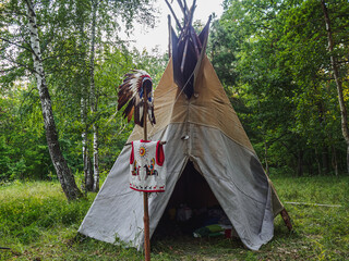 Forest home of the Indians. Wigwam indian teepee. The life of nomadic tribes. The wigwam stands in the forest. A hut of nomadic peoples. A home of Indians. tippi aka in the forest. © alexander_volkov