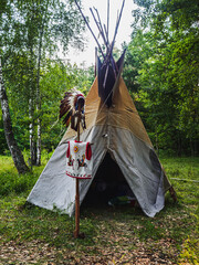 Forest home of the Indians. Wigwam indian teepee. The life of nomadic tribes. The wigwam stands in the forest. A hut of nomadic peoples. A home of Indians. Teepee in the forest. vertical © alexander_volkov