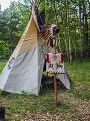 Forest home of the Indians. Wigwam indian teepee. The life of nomadic tribes. The wigwam stands in the forest. A hut of nomadic peoples. A home of Indians. Teepee in the forest. vertical © alexander_volkov