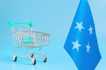 Empty metal shopping basket and the flag of the Federated States of Micronesia on a colored...