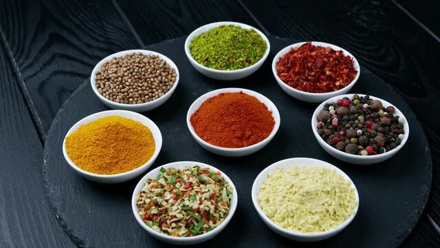 Colorful herbs and spices for cooking. Indian spices. On a black background. Top view